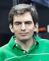 A headshot of Alex who wears a green polo short and looks to the camera